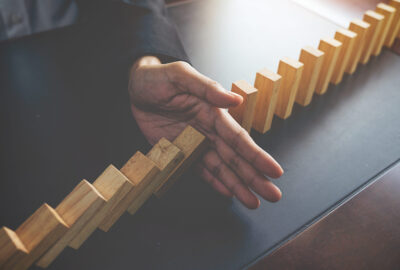 Problem Solving,Close up view on hand of business woman stopping falling blocks on table for concept about taking responsibility.