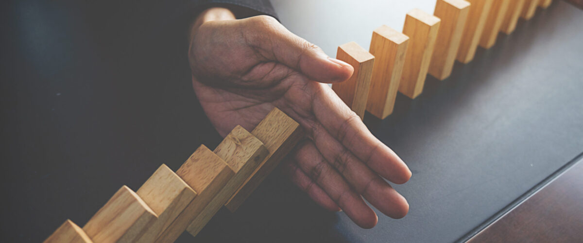 Problem Solving,Close up view on hand of business woman stopping falling blocks on table for concept about taking responsibility.